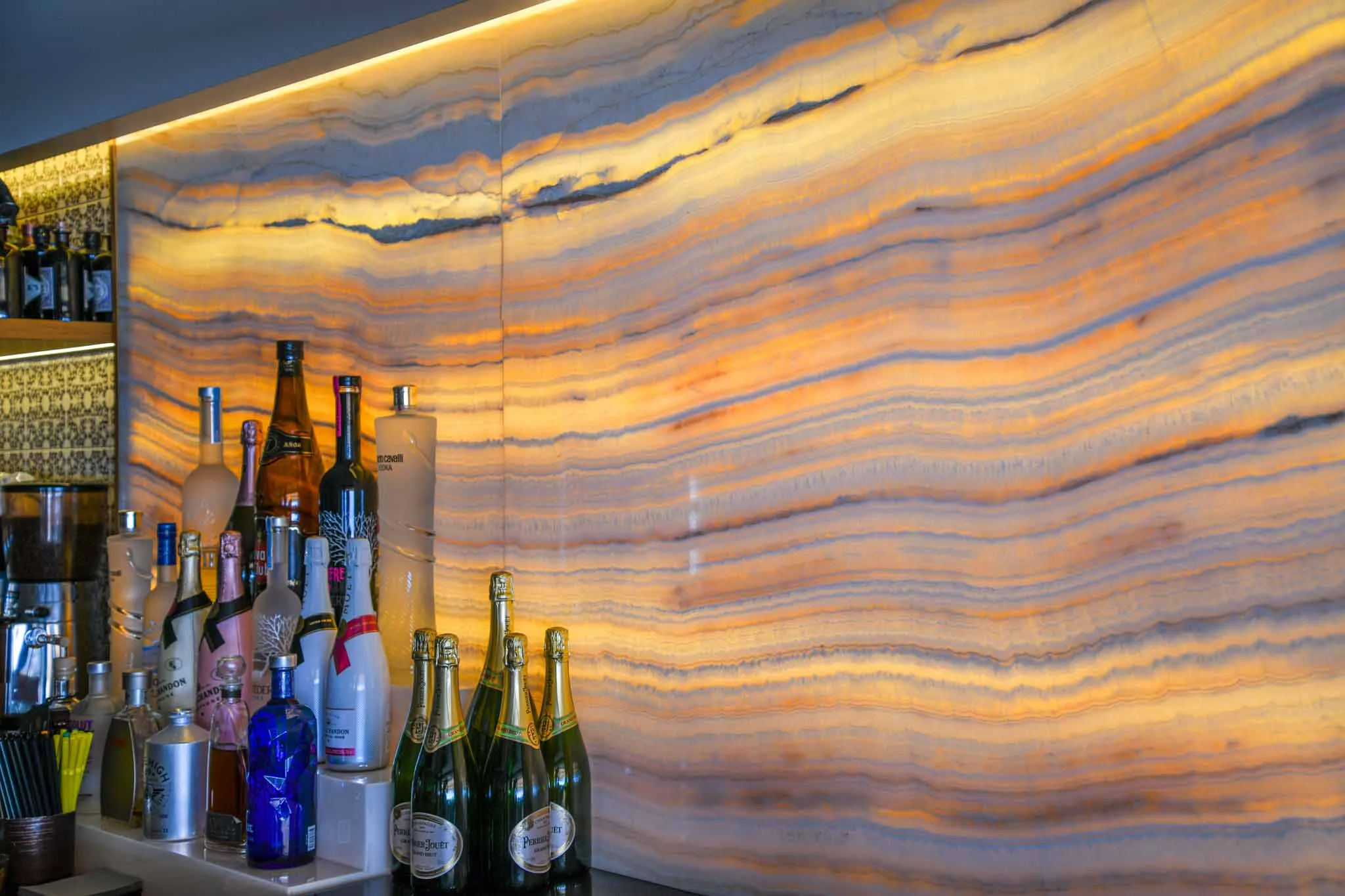 Die hinterleuchtete Onyxwand der Bar, davor Flaschen und Champagner